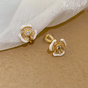 Detailansicht der 18 Karat vergoldeten Blumen-Ohrclips mit weißem Emaille und Zirkonia.