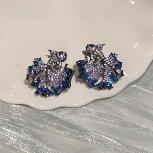 Macro view of exquisite koi fish stud earrings set with blue and purple cubic zirconia stones