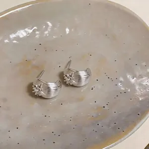 Vue détaillée des boucles d'oreilles argentées avec placage or 18k et fleur en zircon