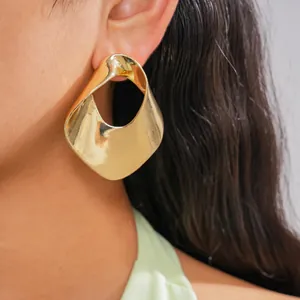 Detailed view of fashionable chunky hollow gold metal earrings worn by a female model