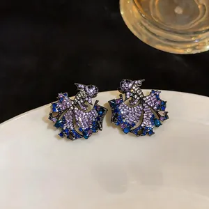 Close-up of vintage carp stud earrings with purple and blue cubic zirconia stones