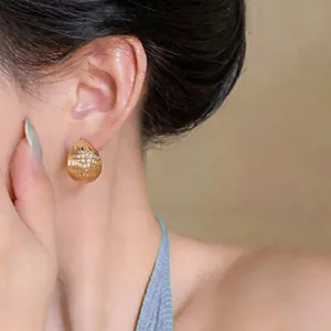 Détail de la boucle d'oreille en goutte dorée avec un motif étoilé en zircon brillant