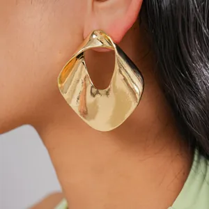 Close-up of chunky gold hollow geometric earrings on model's ear for premium look