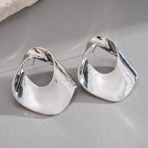 Macro view of irregular hollow silver earrings with high-gloss metallic finish