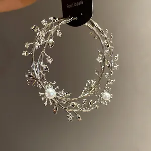 Detailansicht der silberfarbenen Ast-Creolen mit aufwendigen Blumen- und Perlenmotiven.