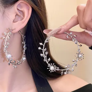 Detailansicht eleganter silberner Zweig-Ohrringe, verziert mit weißen Perlen und kleinen Blumen