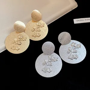 Detailed view of textured round metal earrings with embossed floral branch design