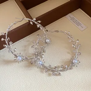 Detailansicht der silbernen Ast-Ohrringe mit eleganten Perlen und kleinen Blumendetails.