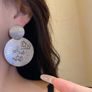 Close-up detail of silver vintage flower pattern on textured metal earrings