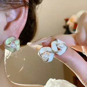 Primo piano di eleganti orecchini a perla a fiore intrecciato con smalto glitterato