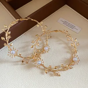 Detailansicht eleganter vergoldeter Ast-Ohrringe mit Perlen und kleinen Blumenakzenten