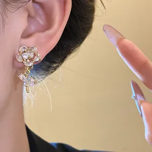 Detailed close-up of elegant 14k gold plated zircon flower earring worn on an ear