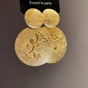 Exquisite macro detail of gold textured round earrings with embossed floral pattern