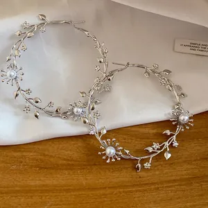 Detailansicht eleganter silberner Ast-Ohrringe mit Perlen- und Blumendetails.