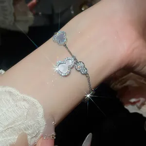 Gros plan des breloques gourde en zircon et nacre étincelantes sur un bracelet argenté