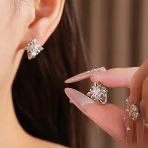 Detailed view of silver iris flower cross earrings with sparkling white zircon stones