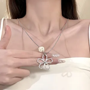 Close-up detail of a silver hollow flower necklace with white pearl accent on a model's neck
