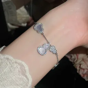 Gros plan de breloques en nacre et zircon étincelant sur un délicat bracelet en argent
