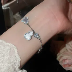 Vue détaillée d'un élégant bracelet en argent avec zircons et breloques en nacre en forme de hulu