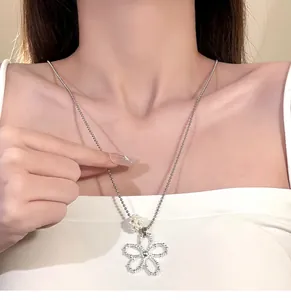 Elegant silver hollow flower pendant necklace with pearl detail shown in close-up view