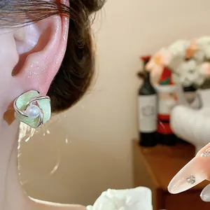 Dettaglio di un orecchino a perno a forma di fiore ritorto in smalto verde chiaro