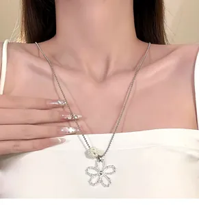 Detail shot of a silver hollow flower necklace with a pearl bead on a model's neck