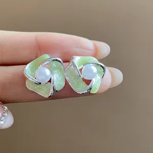 Primo piano di orecchini a fiore in argento con smalto verde e dettaglio perla