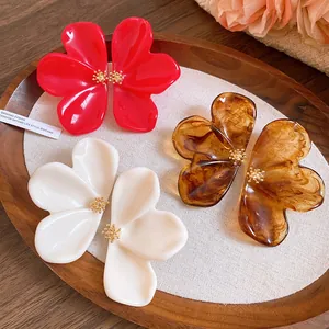 Close-up of stylish resin flower stud earrings in red, white and marbled amber finishes.