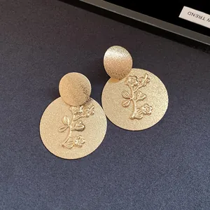Detailed view of gold textured round earrings with embossed floral design