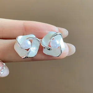 Dettaglio di orecchini a fiore intrecciato con perle centrali e petali perlati bianchi
