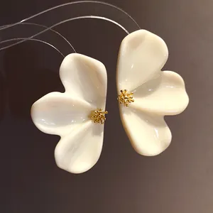 Detailed view of cream resin flower stud earrings with golden textured centers