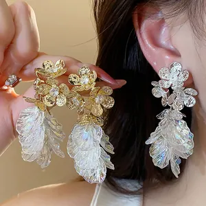 Macro detail of 18k gold plated flower earrings with layered iridescent petal tassels