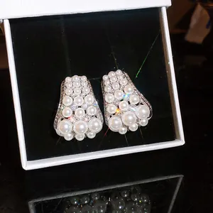 Macro view of French vintage stud earrings featuring white pearls and sparkling zircons