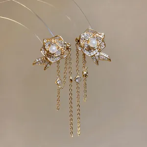 Nahaufnahme von eleganten 18K vergoldeten Zirkonia-Rosenohrringen mit langen Quasten-Ketten