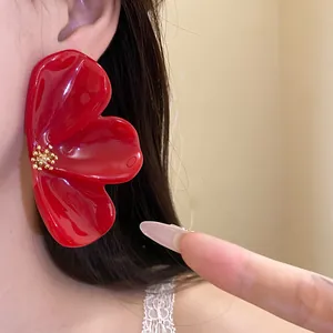 Macro view of a large red resin flower earring worn on an ear