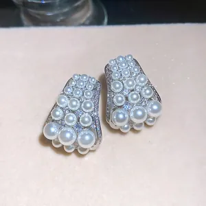 Detailed macro shot of elegant French retro pearl and zircon cluster earrings on soft background