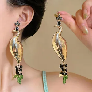 Detailed view of vintage peacock drop earrings with black gems and green beads.