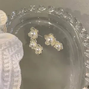 Close-up of vintage French style asymmetric pearl earrings on a clear glass tray