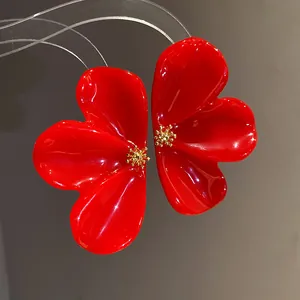 Detailed view of red resin flower stud earrings with elegant gold center accents.