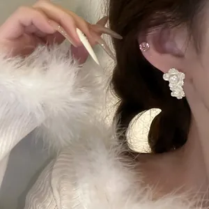 Detail view of elegant French vintage white flower pearl earrings worn by a model