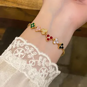 Close-up of a gold-colored bracelet with colorful zircon-set flower charms on a wrist