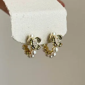 Detail of gold-plated hoop earrings with pearls and a sparkling zircon butterfly motif