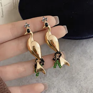 Close-up of elegant vintage gold peacock earrings featuring green beads and crystal accents