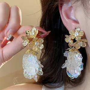 Close-up detail of 18k gold plated flower stud earrings with iridescent tassel fringe