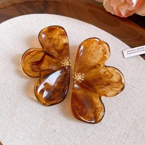 Macro detail of amber marble resin flower stud earrings with gold floral centers