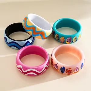 Close-up of vibrant resin bangles featuring wavy patterns and colorful fish prints