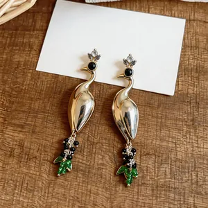 Detailed close-up of vintage gold peacock earrings with rhinestones and green pendants.