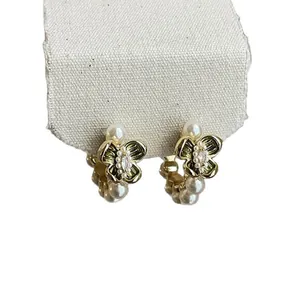 Detail of gold-tone flower hoop earrings featuring pearls and sparkling zircon stones.