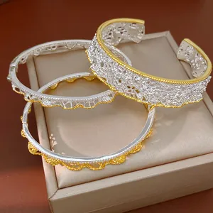 Primo piano di tre braccialetti traforati in pizzo retrò francese in oro e argento