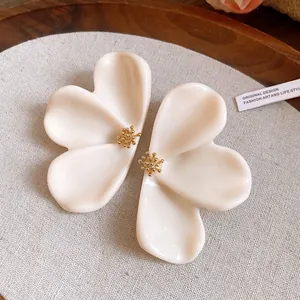 Macro view of creamy white resin flower petal earrings with golden stamen detail